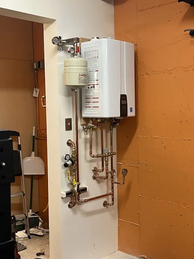 Plumbing technician inspecting water heater connections in St. Francis